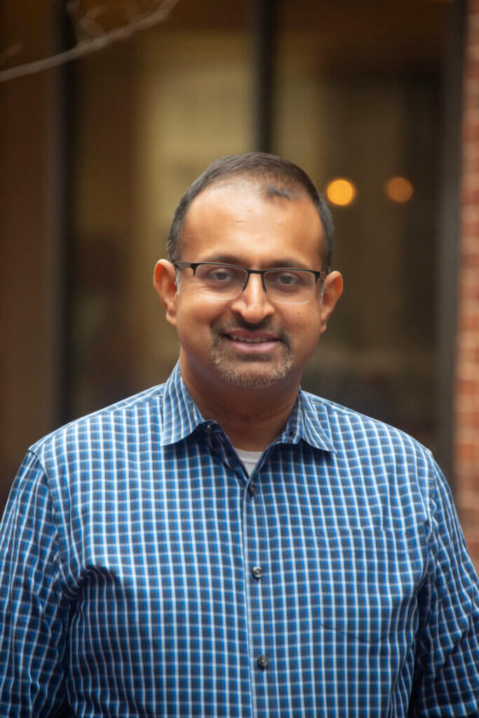 Debashish Chakravarty, VOANS Vice President of Real Estate Development, wearing glasses and a blue checkered button up shirt